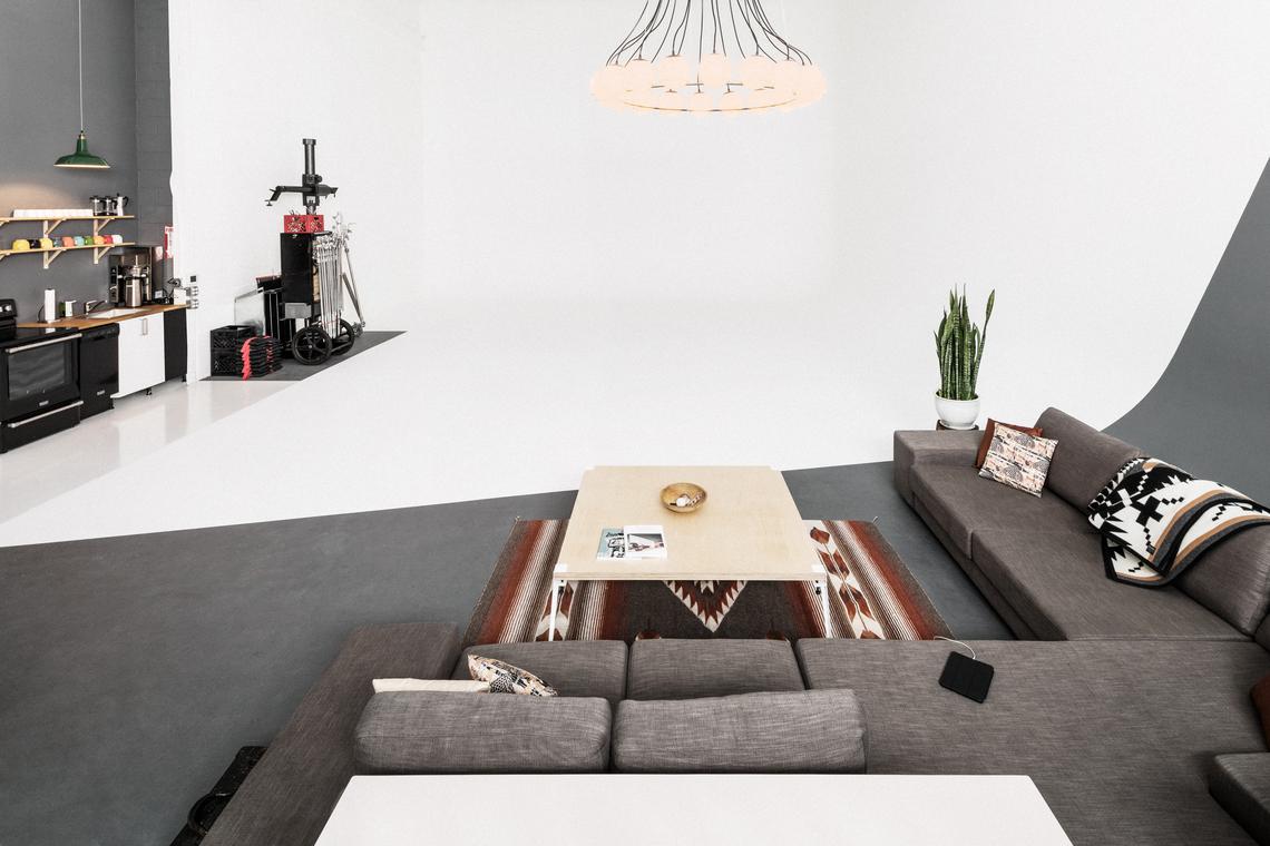 Grey sectional and coffee table on a kilim rug at the edge of the cyc