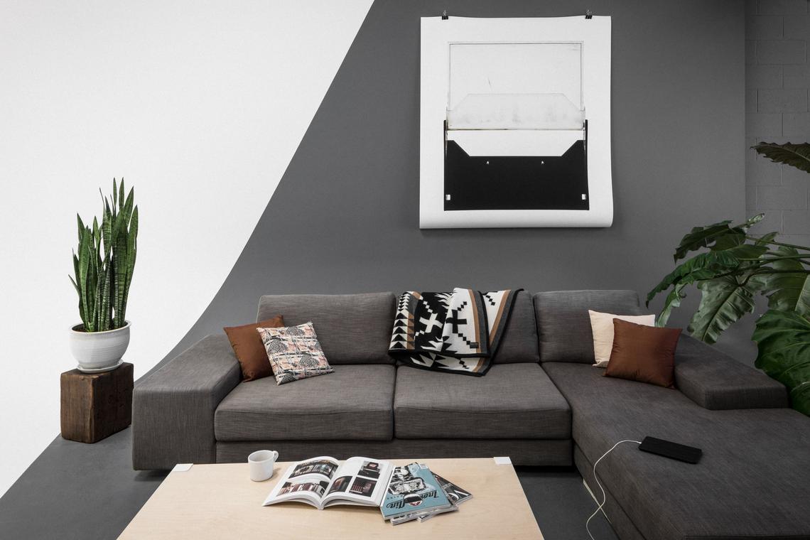 The lounge corner — sectional, pillows, and framed artwork on the charcoal wall