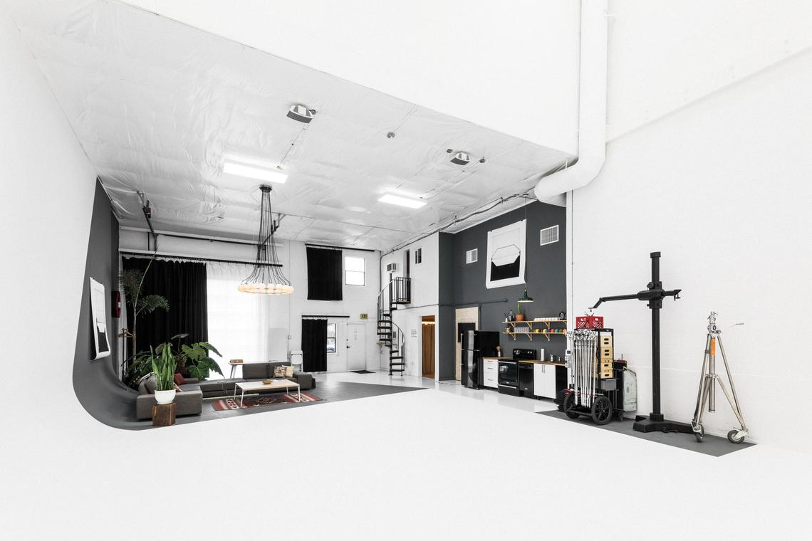Wide view across the cyc — lounge, grip gear, and the spiral stair