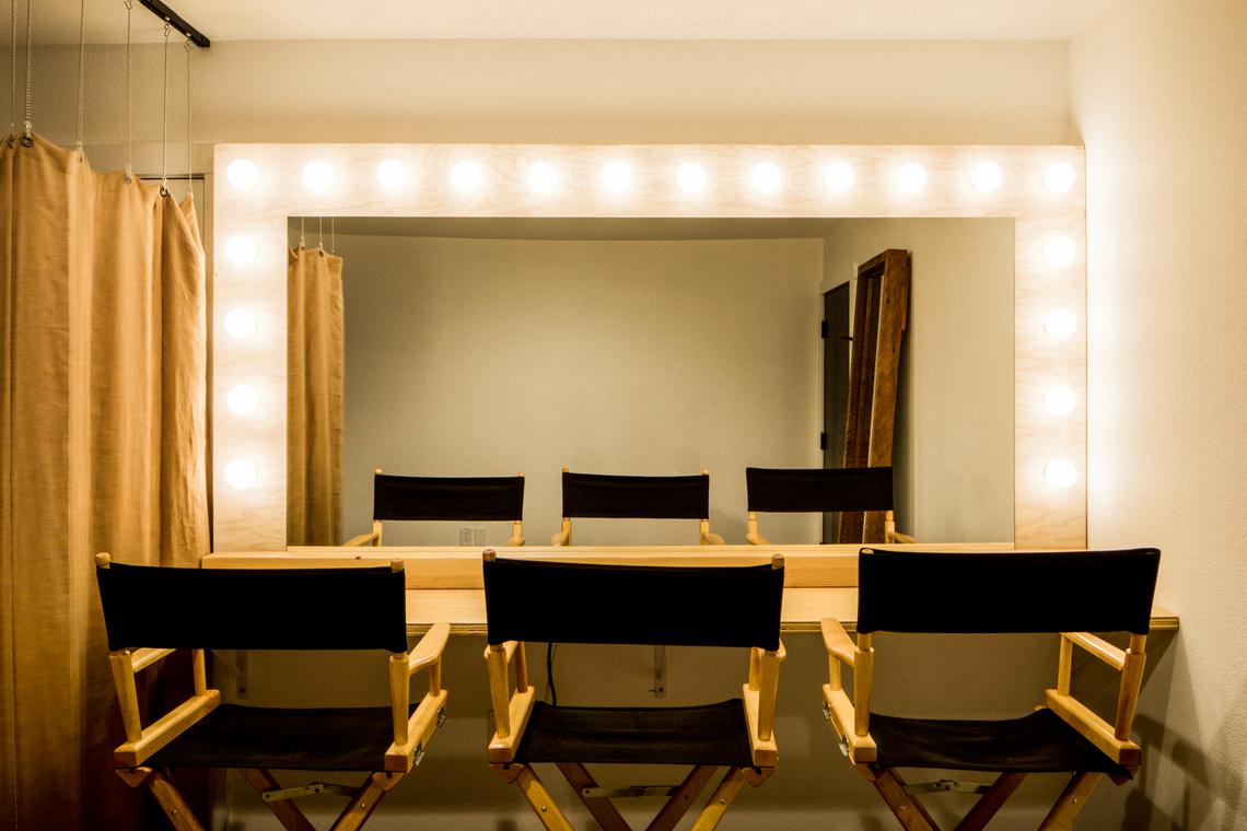 The makeup station — lit mirror and director's chairs