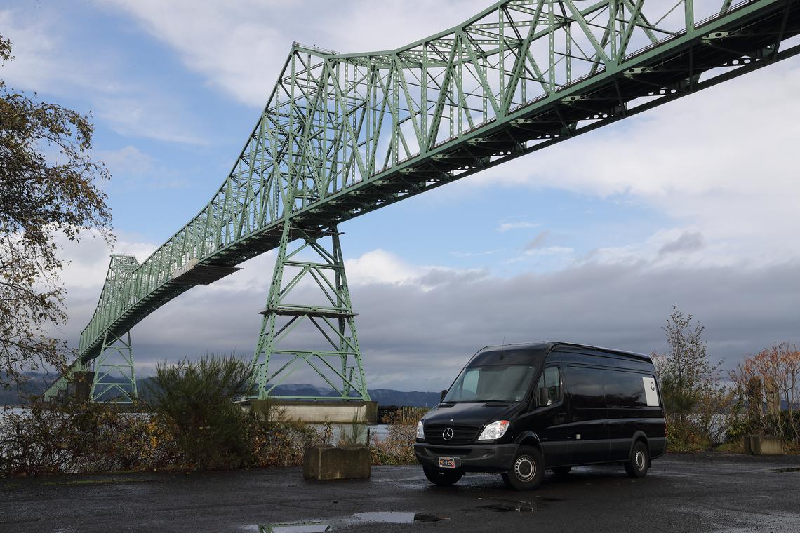 The black Sprinter grip van parked beneath the Astoria–Megler Bridge