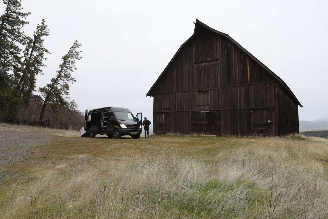 The van, doors open, on location at a weathered barn