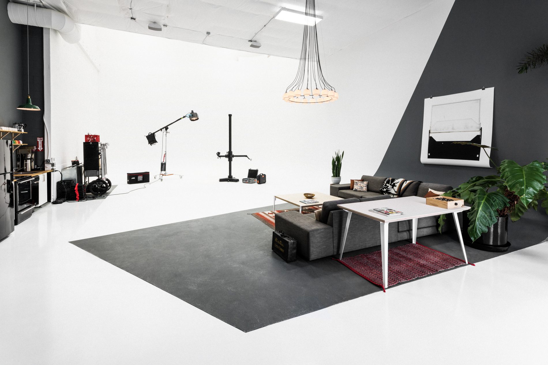 Inside COOLHAND Studio: white cyc, dark concrete wedge floor, lounge corner, and grip gear staged for a shoot